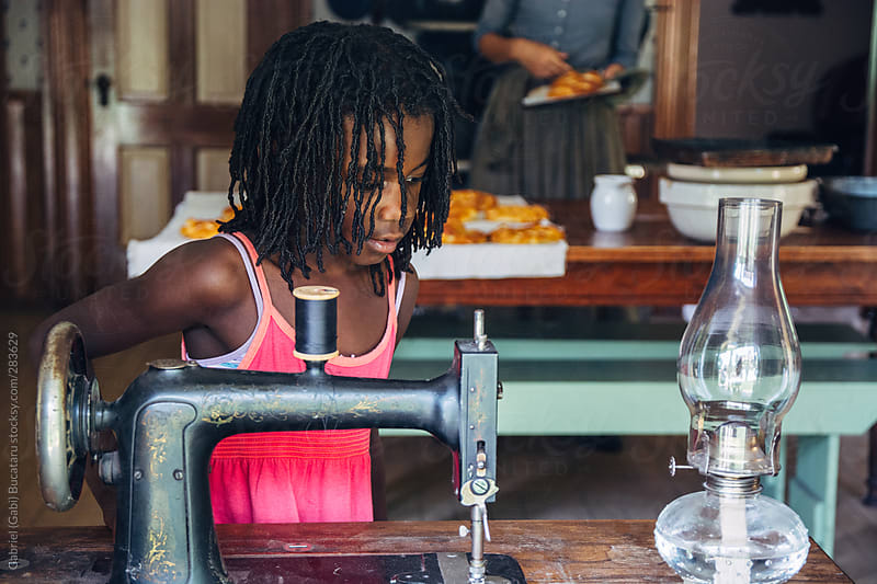 African American Girl Looking At A Vintage Sewing Machine By Gabriel