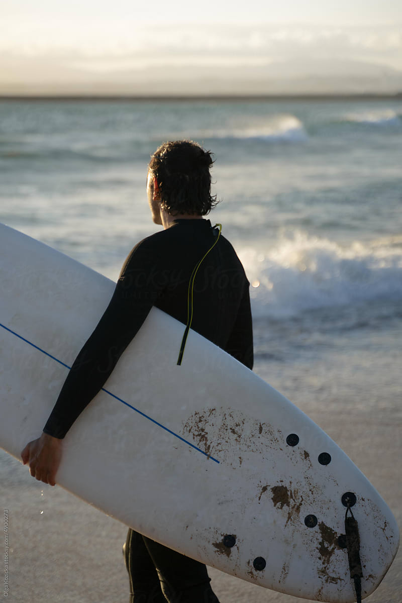 Man Walking Into Ocean With Surfboard