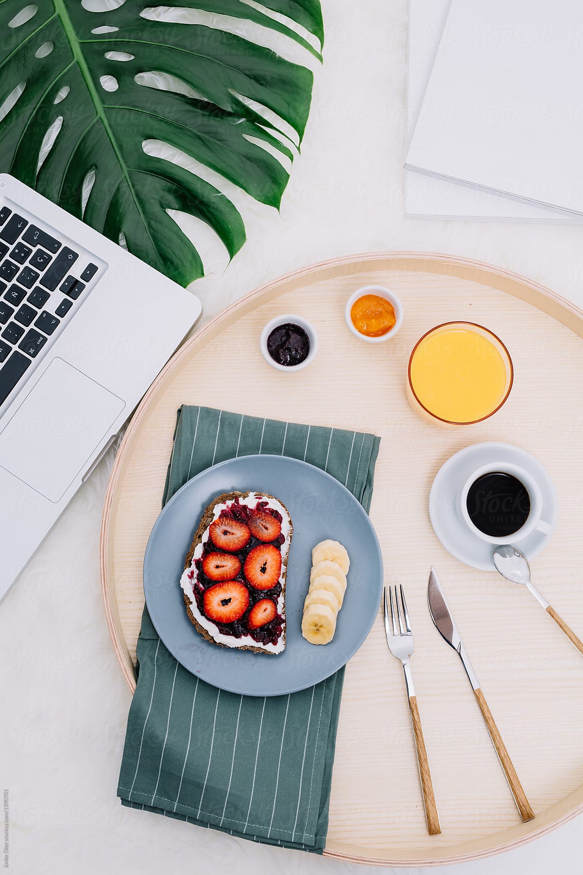 Crop laptop near tray with breakfast