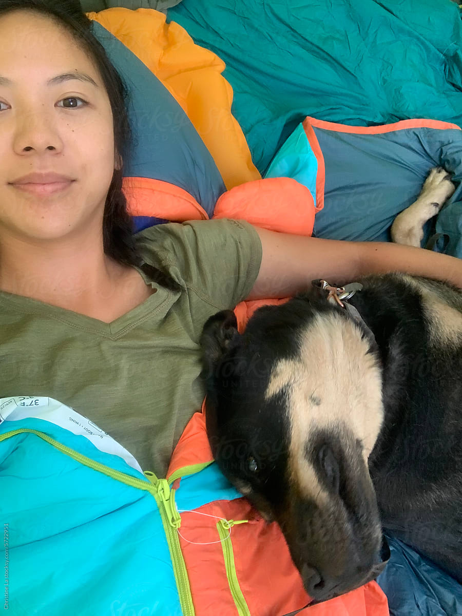 Selfie of girl laying with dog inside camping tent