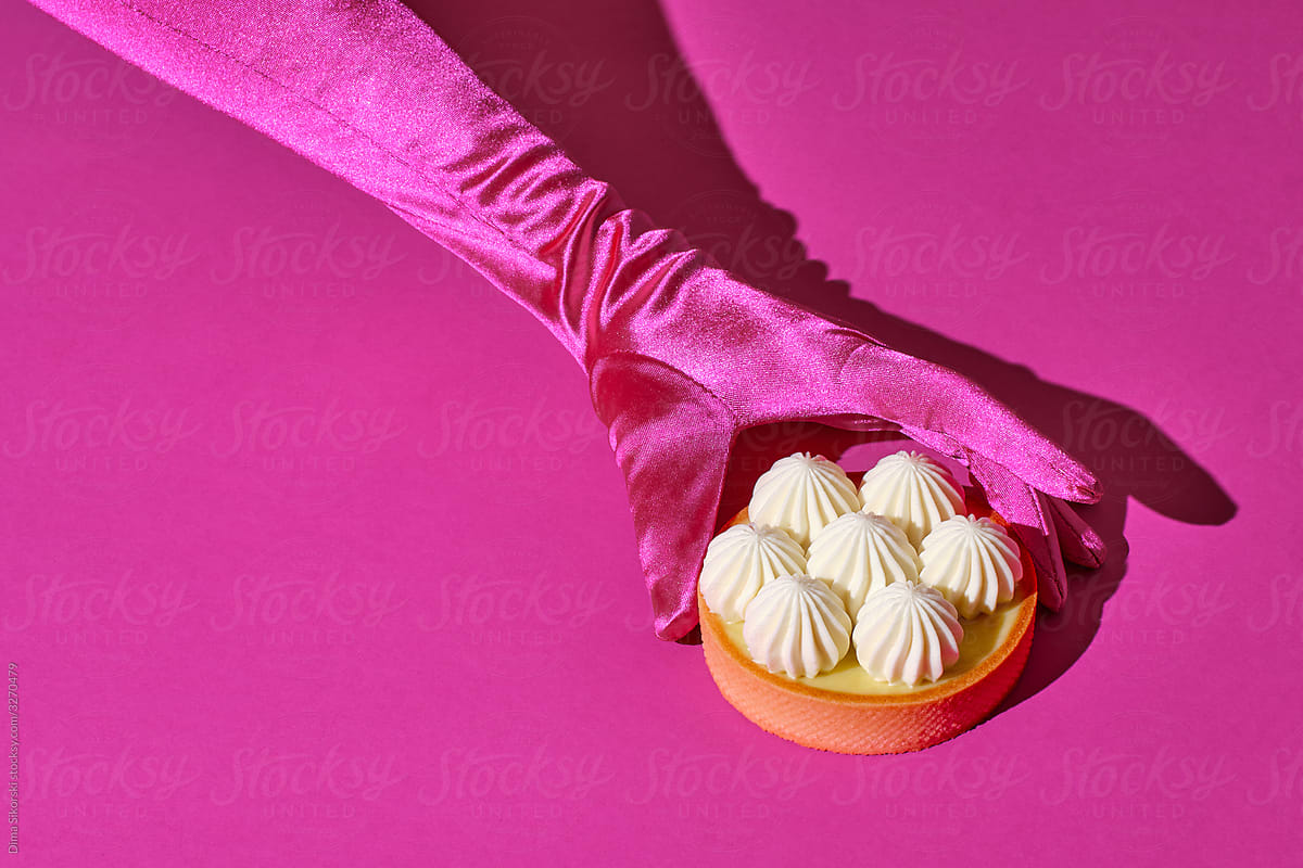 Tart with cream peaks on a pink background. Dessert in a female hand