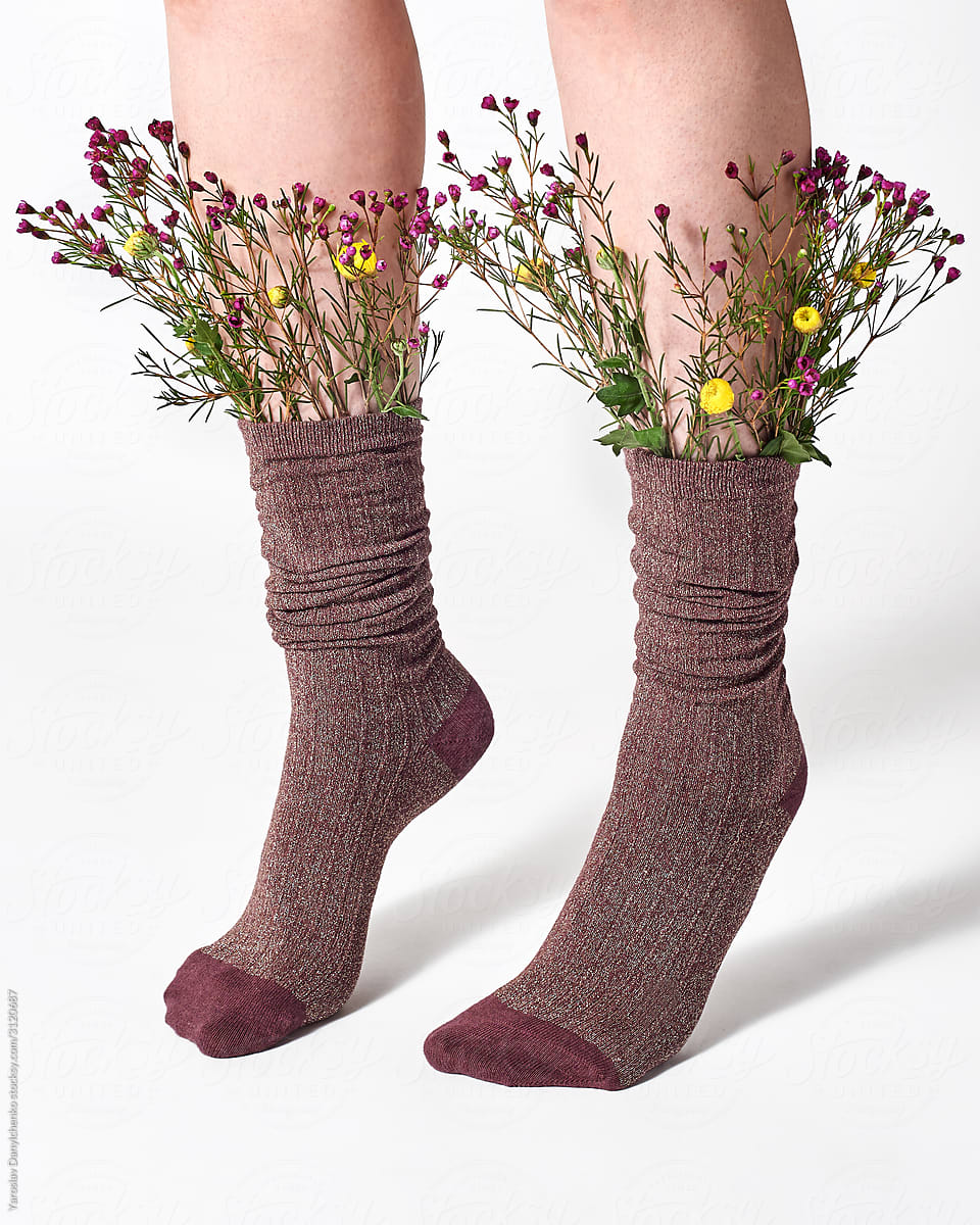 Woman wearing brown socks with wild flowers sticking out.
