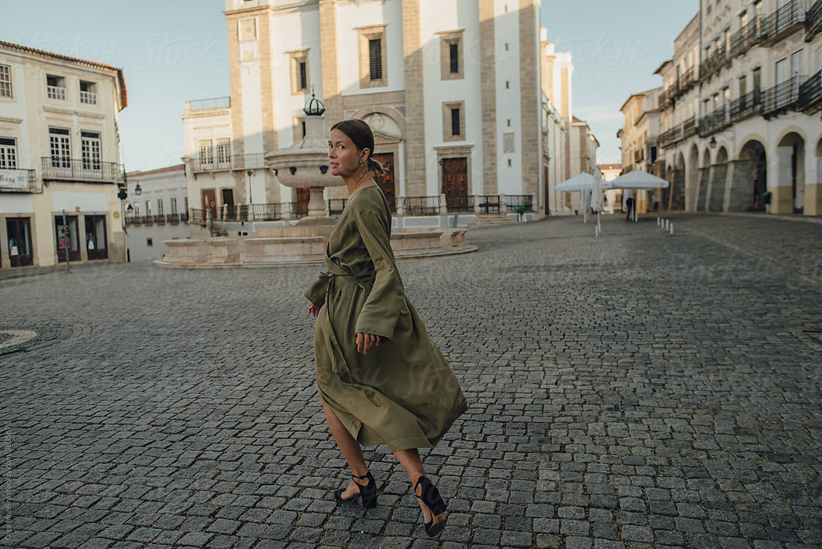 Woman running away from camera on a square of Evora, Portugal