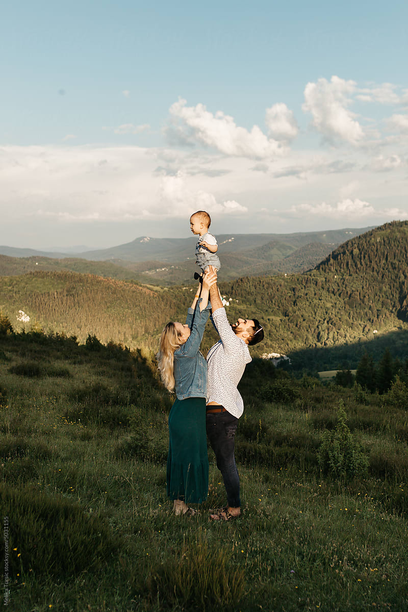 Couple playing with child in nature on a sunny day