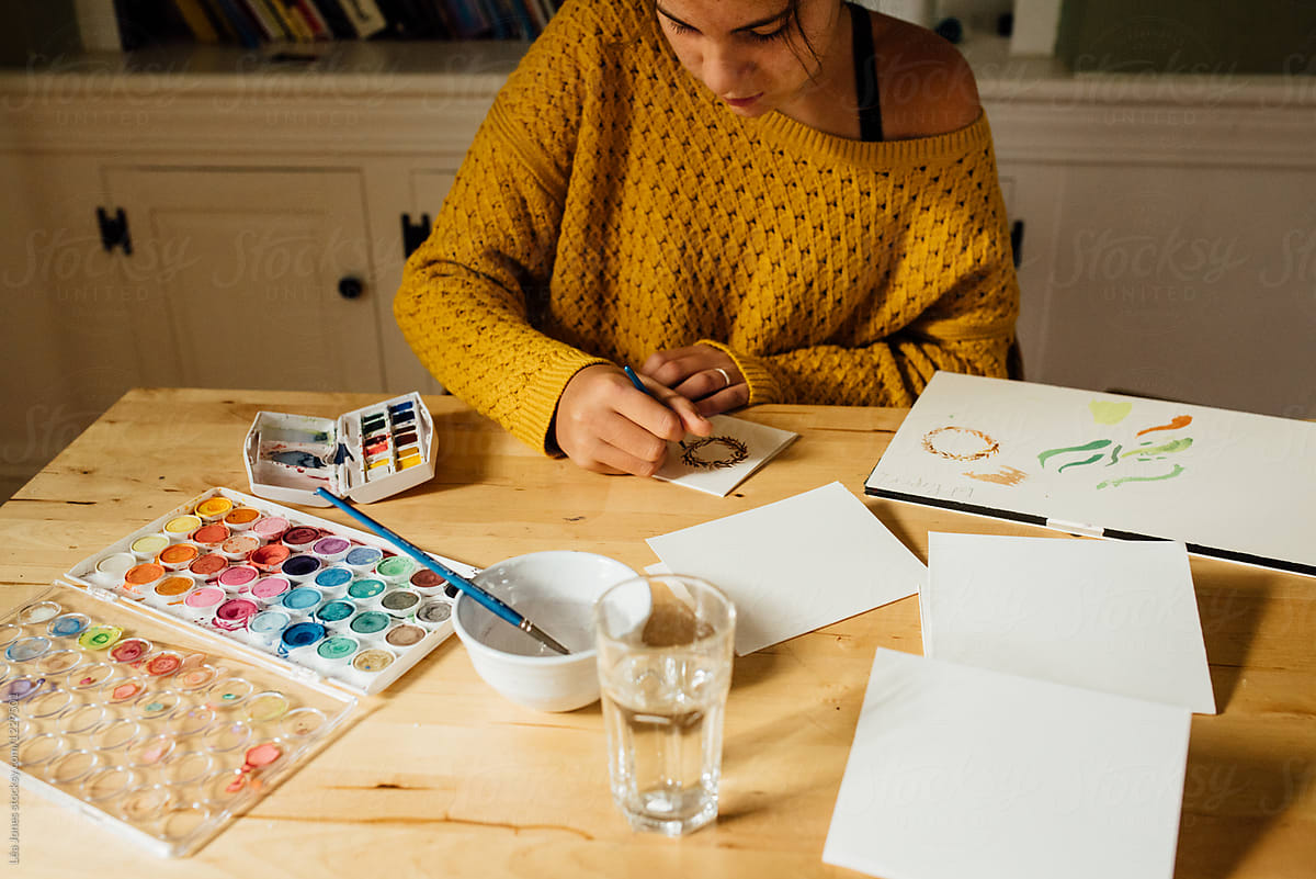 young woman painting cards with watercolours