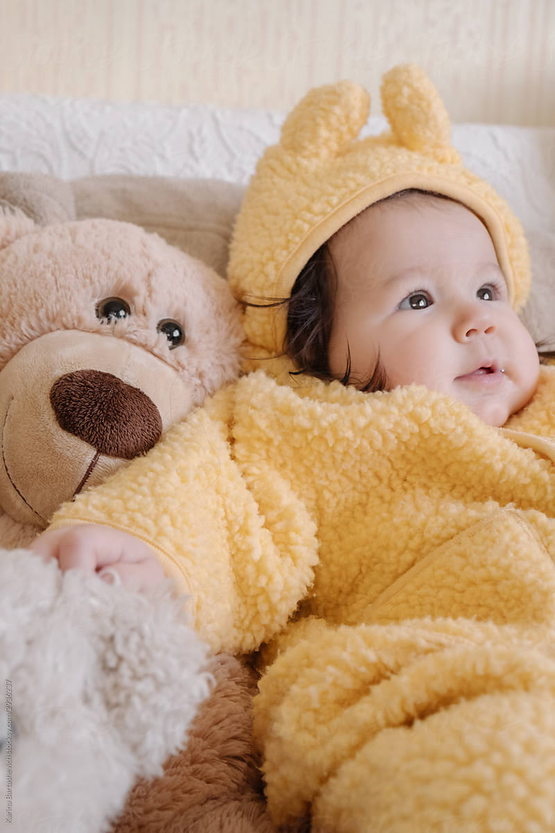 portrait of a little girl next to a toy teddy bear on a bright sofa