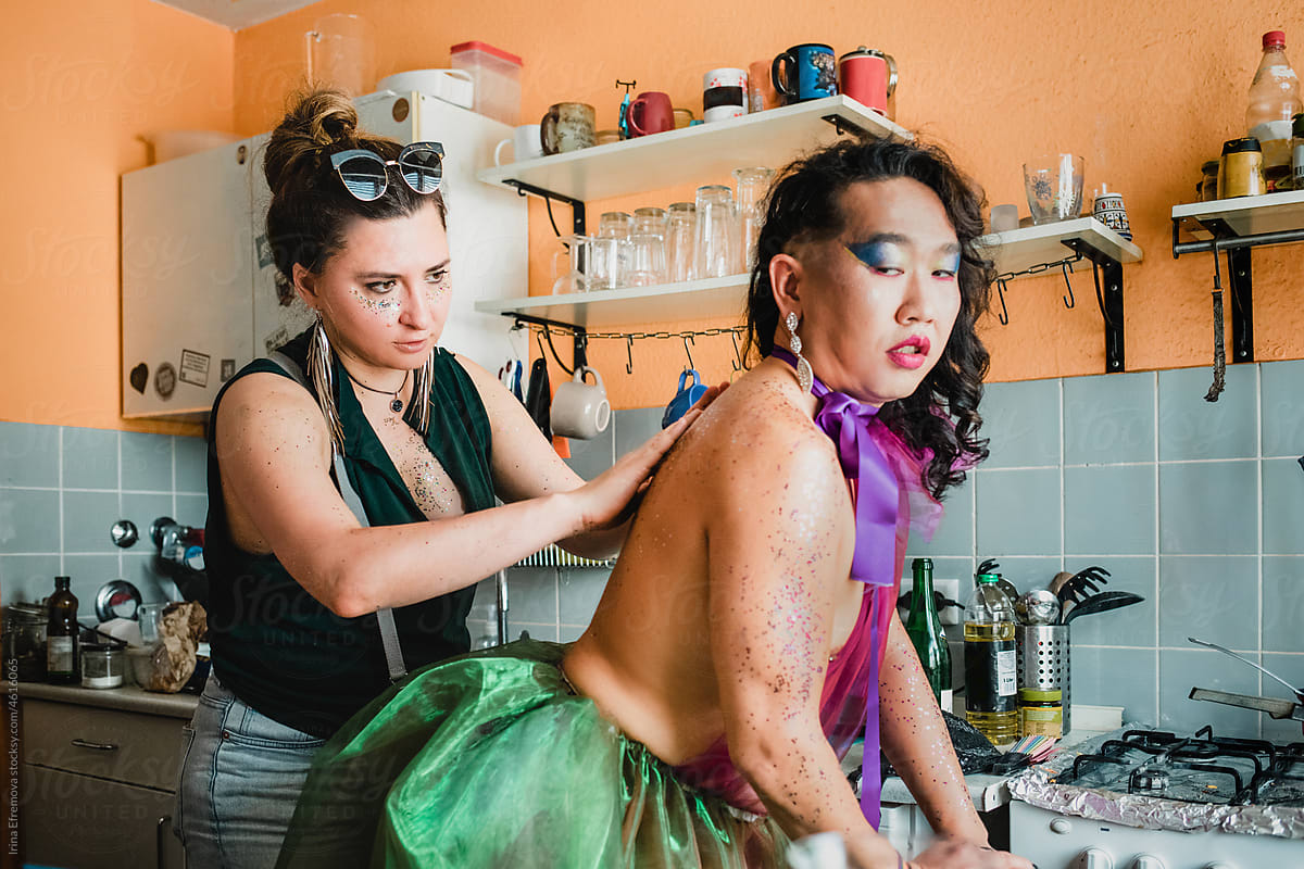 Woman applying glitter on man\'s back in the kitchen