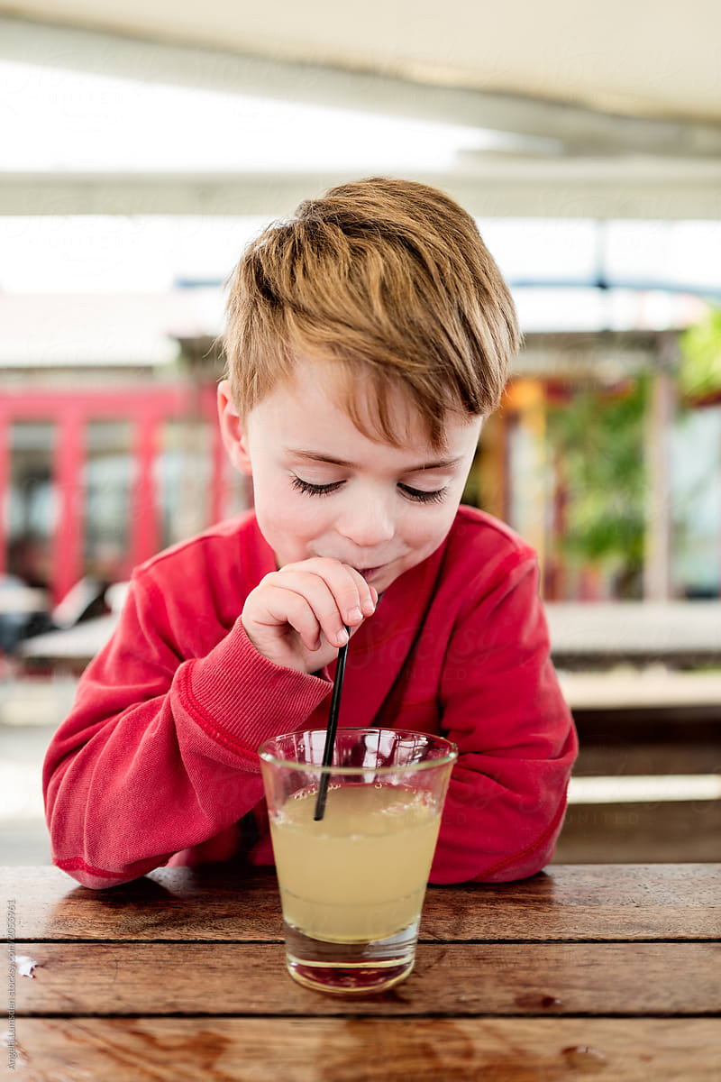 Boy with apple juice at an outdoor table