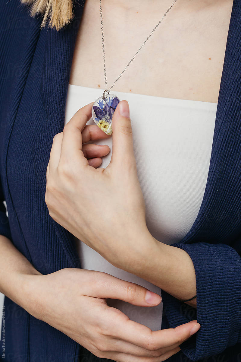 Close up of female hands holding floral epoxy necklace