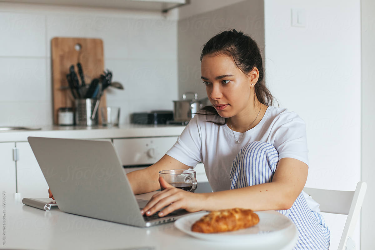 Woman having breakfast and working on a lap top