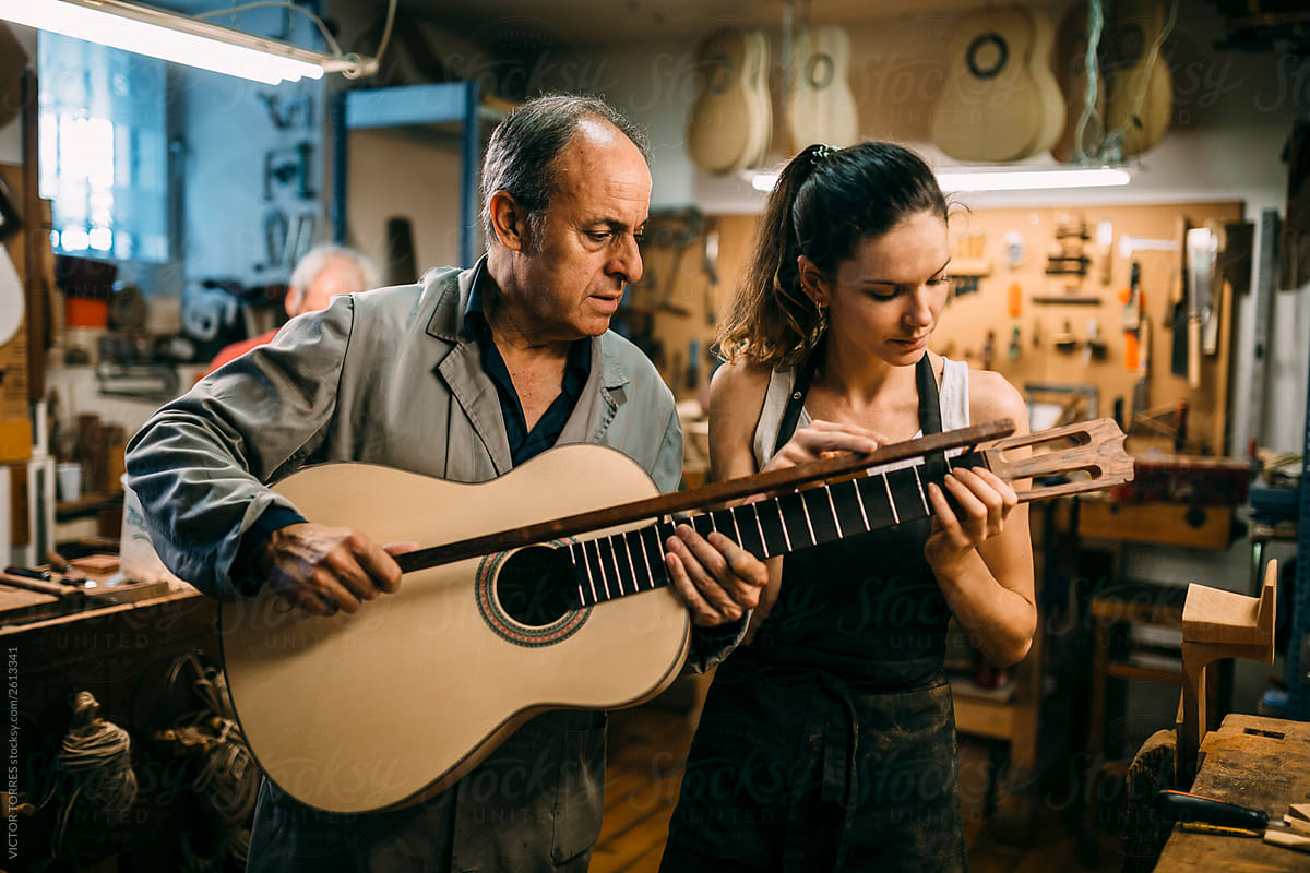 Luthiers checking the finishing of a custom spanish guitar