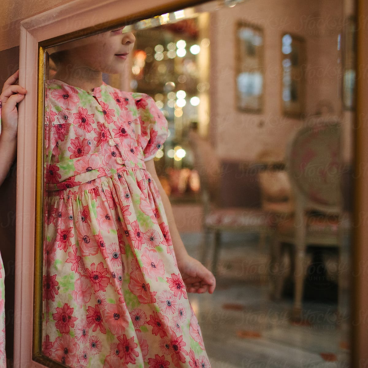 Little girl in party dress seen reflected in a mirror.