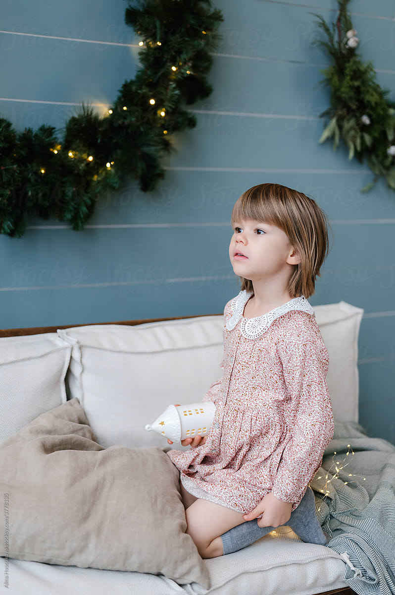 Charming girl on sofa in room with Christmas decorations