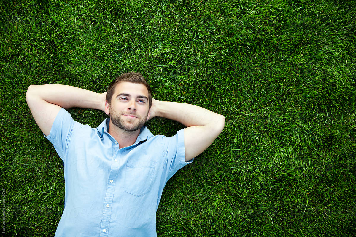 Grass Man Rests On Grass With Hands Behind Head Del Colaborador De