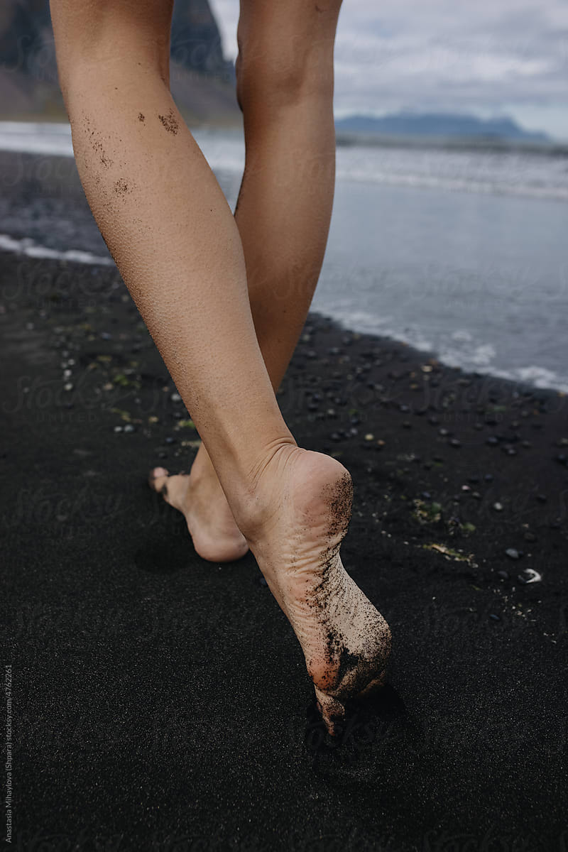 Vertical photo of woman\'s feet Walking On the black Beach in Iceland