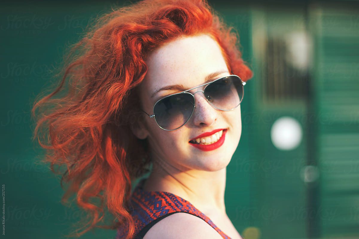 View Ginger Haired Woman With Sunglasses Smiling By Stocksy 