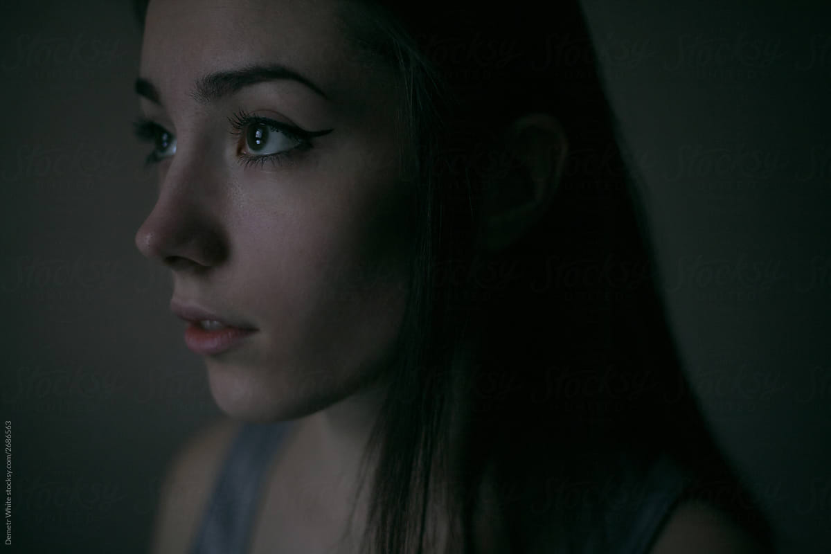 close portrait of the face of a beautiful girl in the dark light