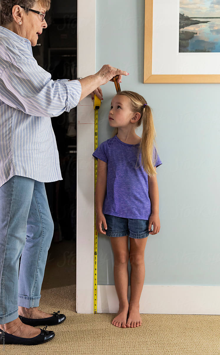 Young Girl Measuring her height and looking at Grandmother