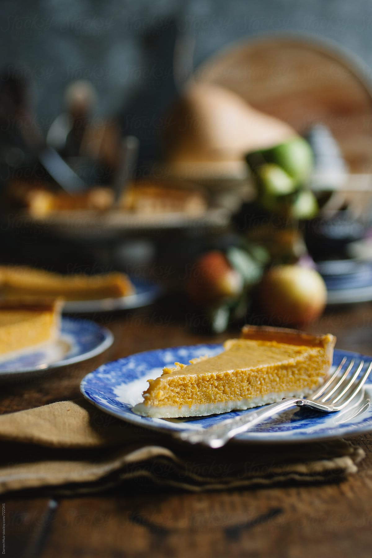 Slice of pumpkin pie on a blue plate on wooden table, selective focus.