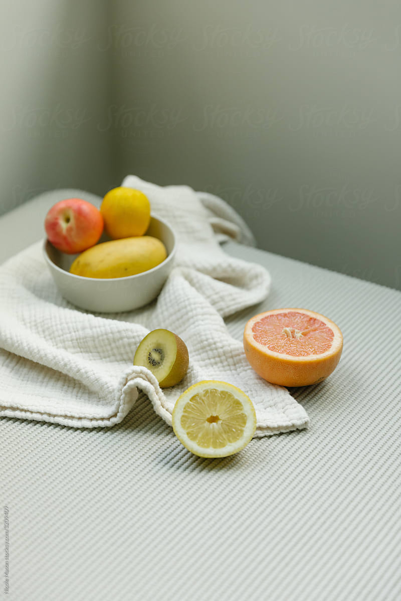 bowl of fruits and slices on table with textured cloth