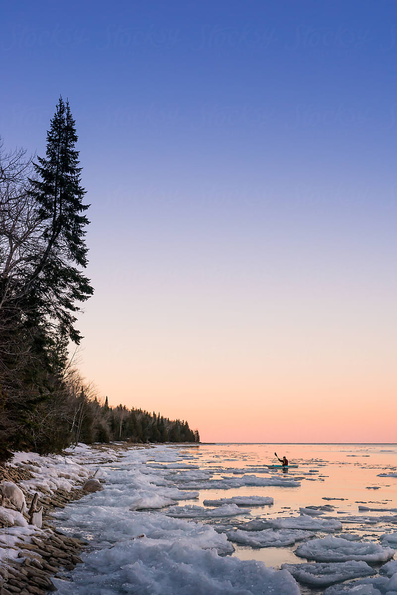 Man kayaks in solitude in Ontario winter landscape
