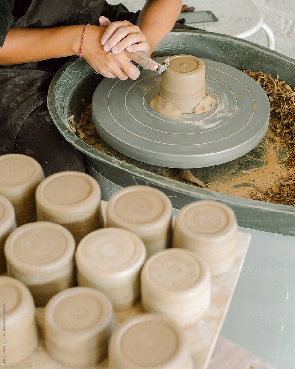 Woman makes a clay mugs on a potter\'s wheel