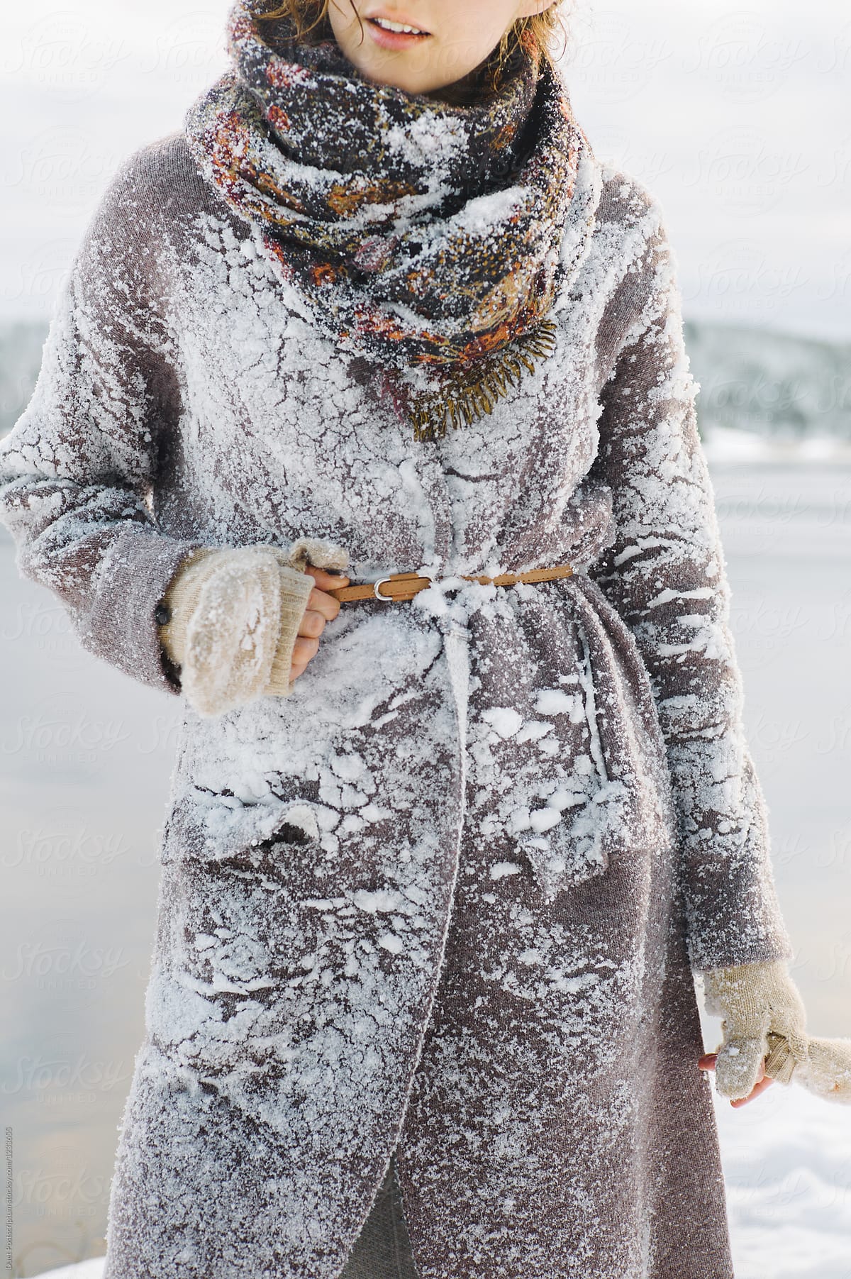 Crop female in coat covered with snow
