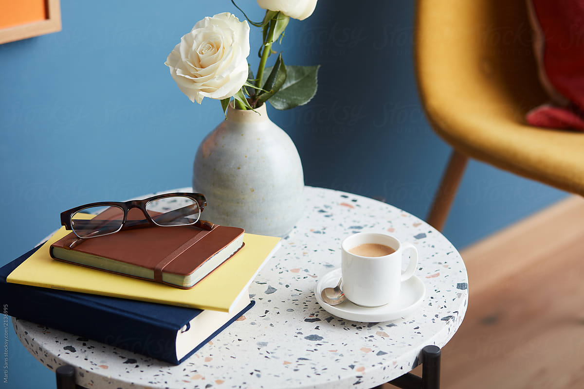 Modern round table with roses, books and coffee.