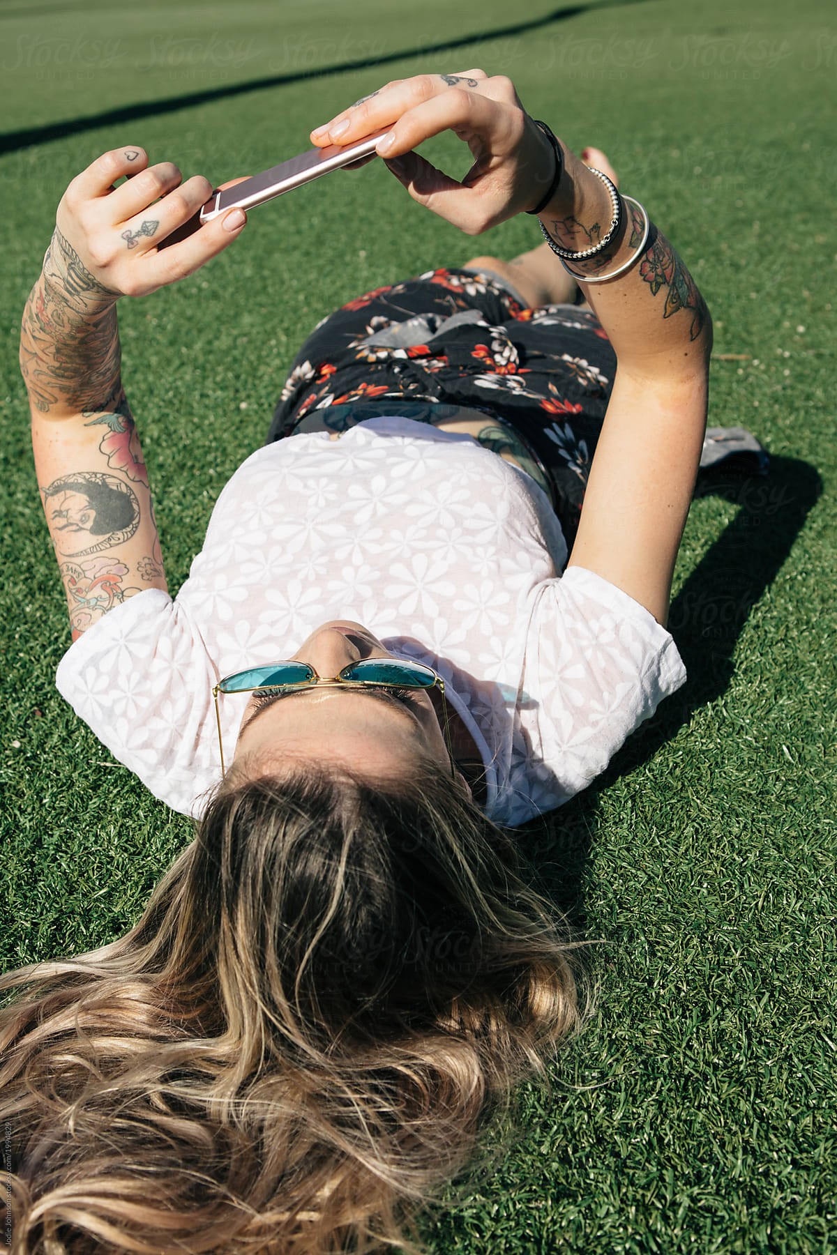Young woman lying on the grass with her phone