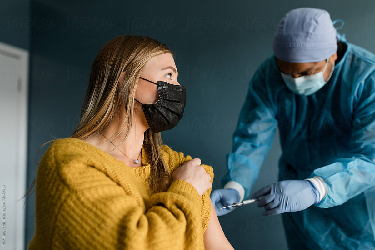 Young Woman Watches Medical Worker as he Gives Her the Covid-19 Vaccine