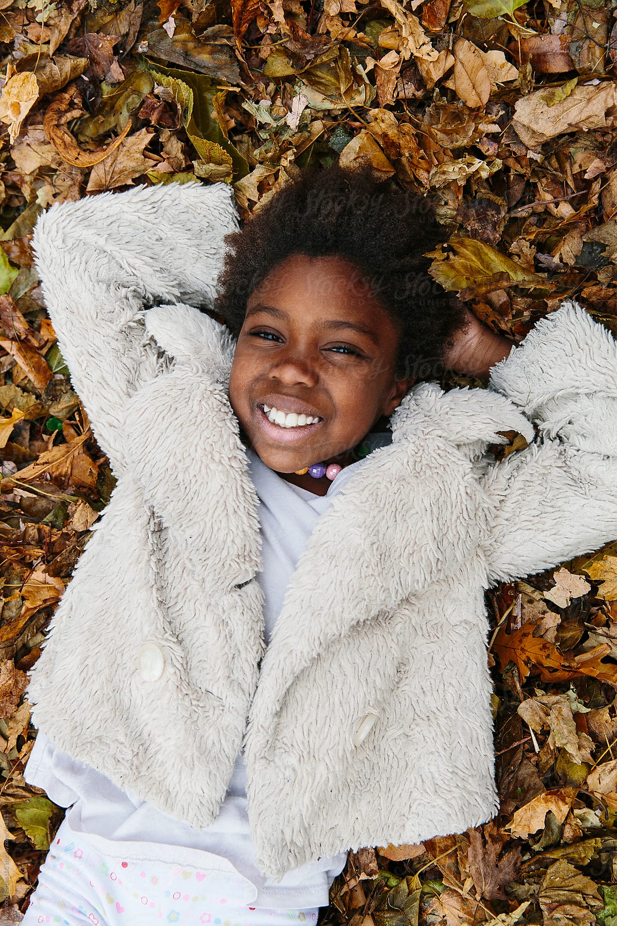 African American Girl Playing in Leaf Pile
