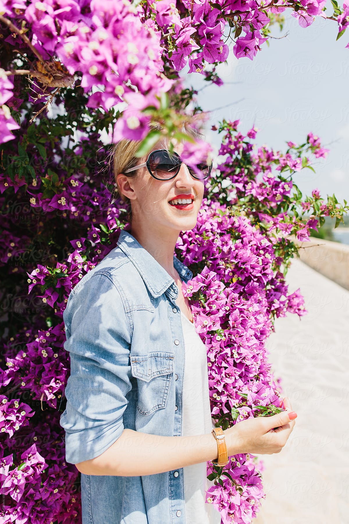 Grinning woman in sun surrounded by purple blooms