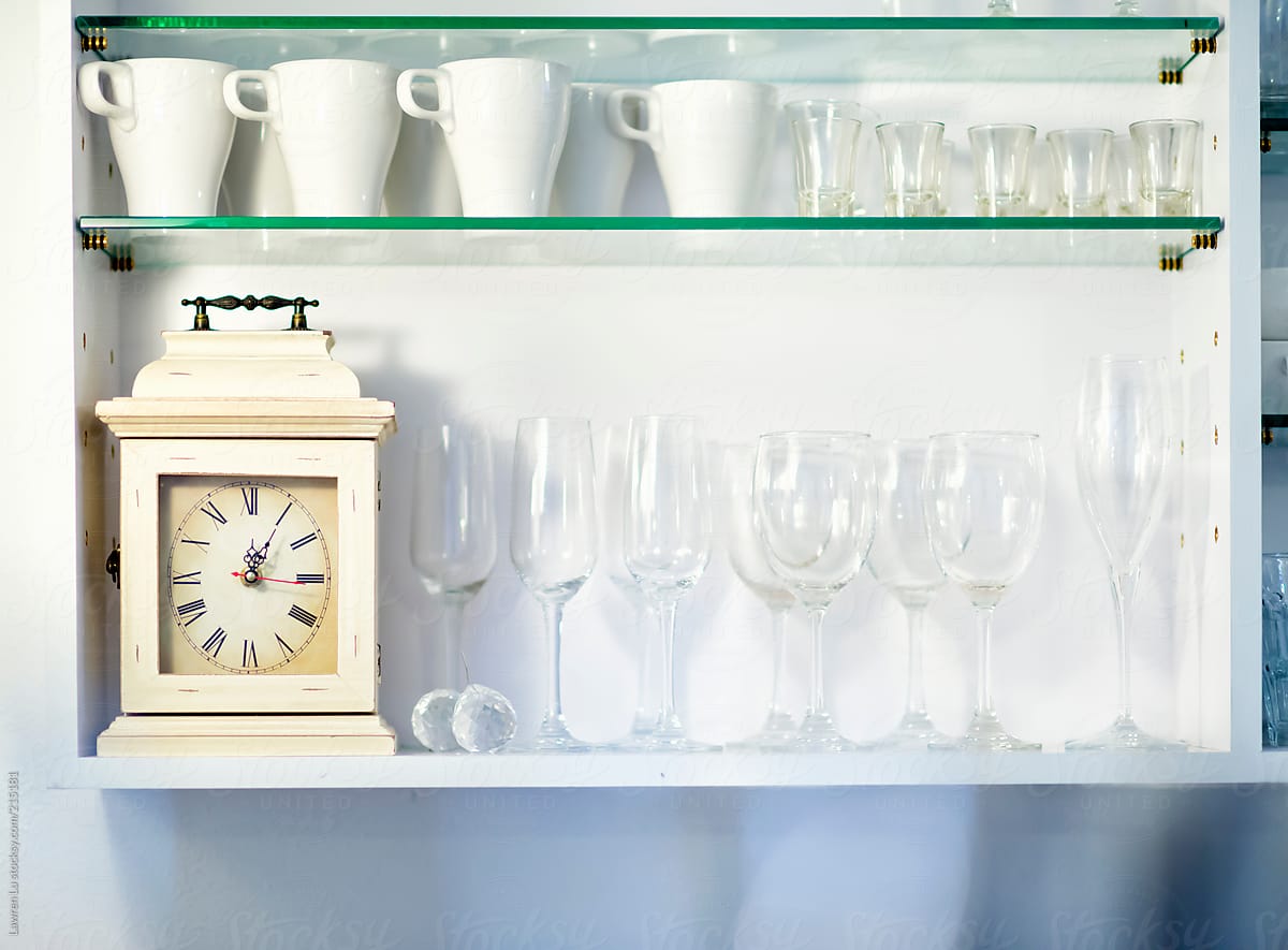 Tidy and neat white cupboard with glasses and vintage clock in restaurant