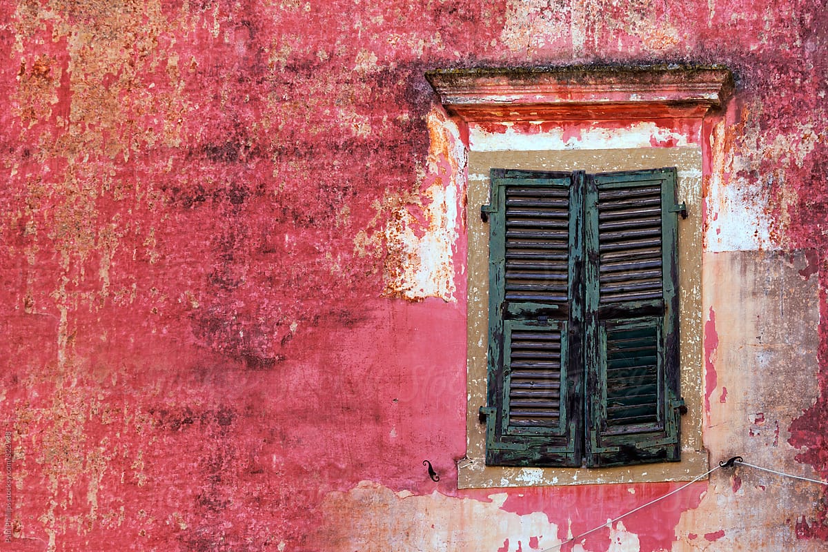 Weathered red paint and green shutters of an old building