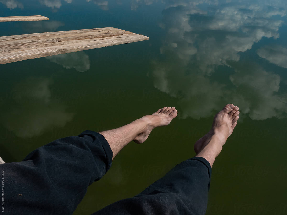 Human legs against the sky reflecting in the water