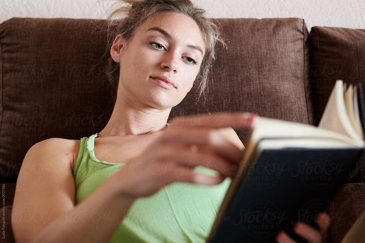 Relaxed Woman Reading Book On Sofa