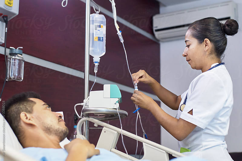 Nurse checking medication in IV drip in patient\'s room