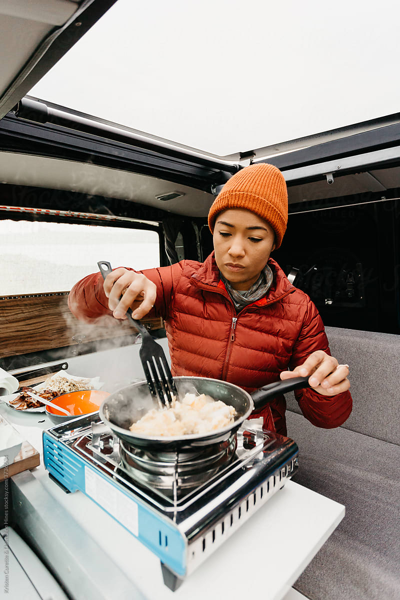 A woman cooking in a camper van