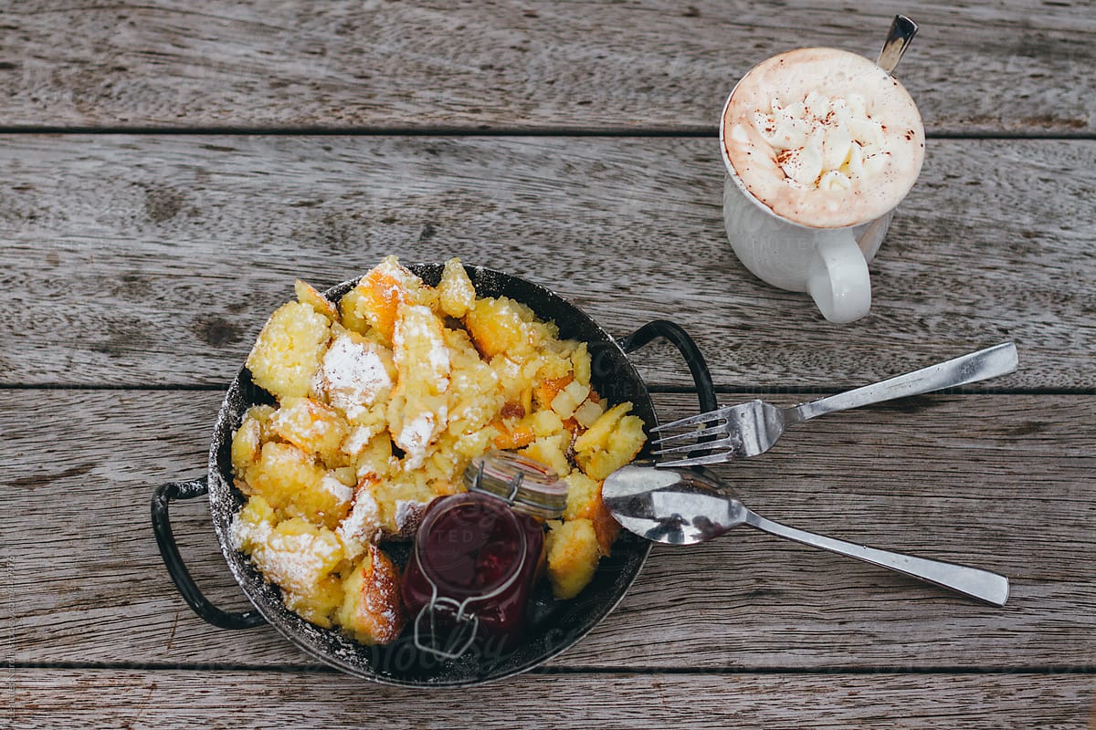 kaiserschmarrn with stewed plums and hot chocolate on wooden background from above