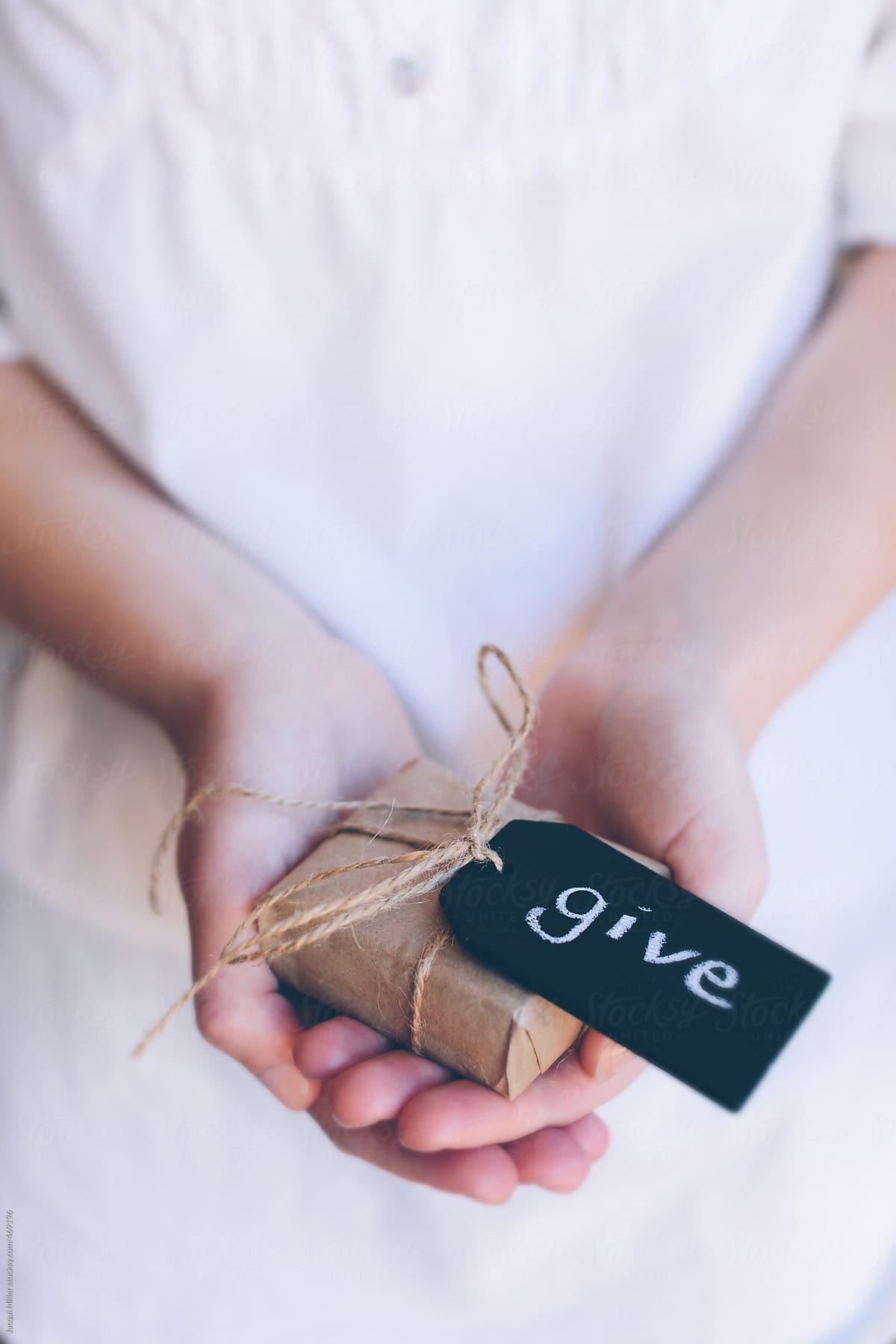 Girls hands holding a gift with the word \'give\' written on a black slate tag