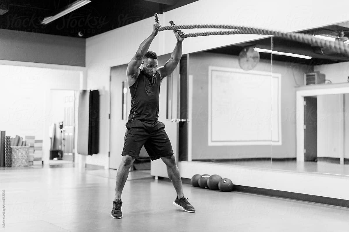 Fit And Muscular African American Athlete Working Out With Exercise Ropes By Stocksy