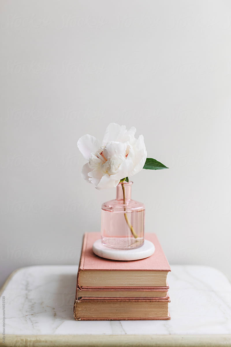 books and a peony in a vase
