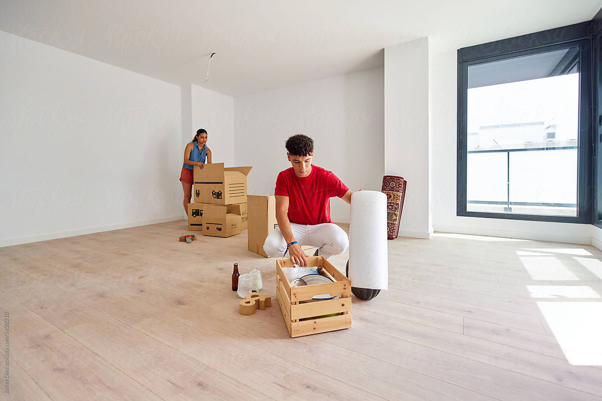 Focused young couple unpacking boxes in empty apartment