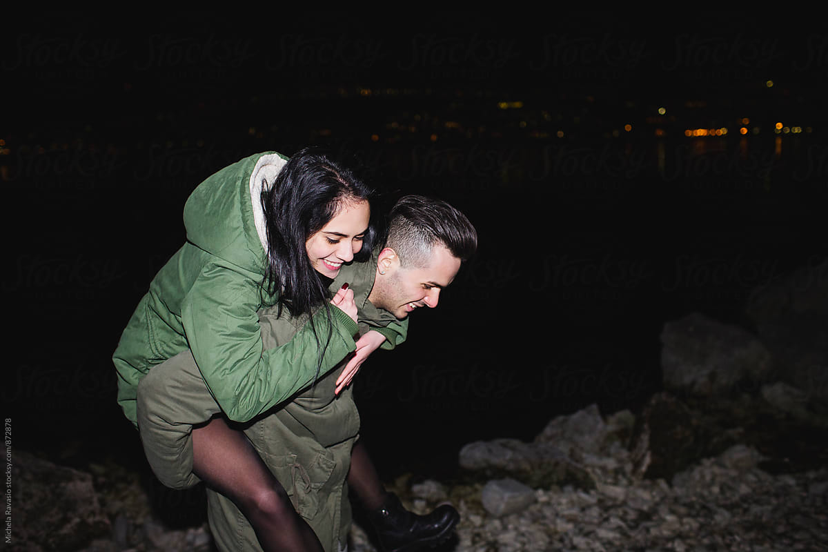 Young couple having fun at the lake at night