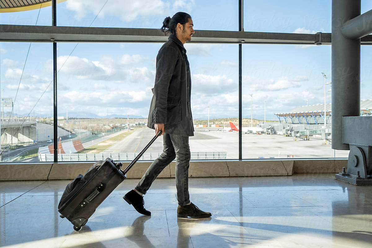 Young Businessman With Suitcase Walking In The Airport Terminal.