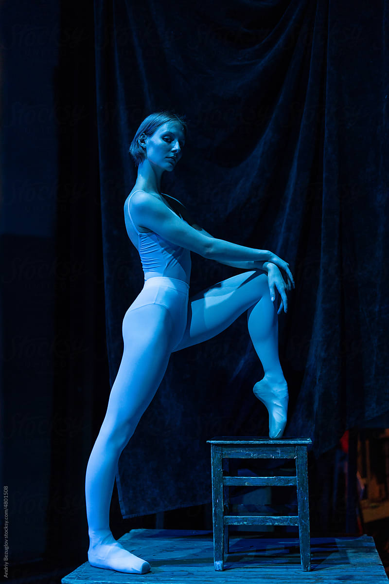 Blue light view of the young ballerina stands in pointe shoes