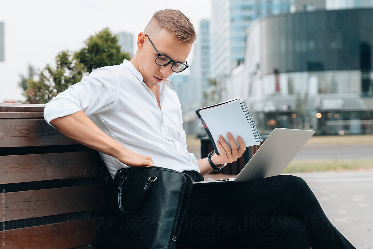 Focused man working online outdoors using laptop for remote job