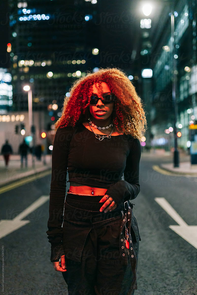 Black female standing on city street in twilight
