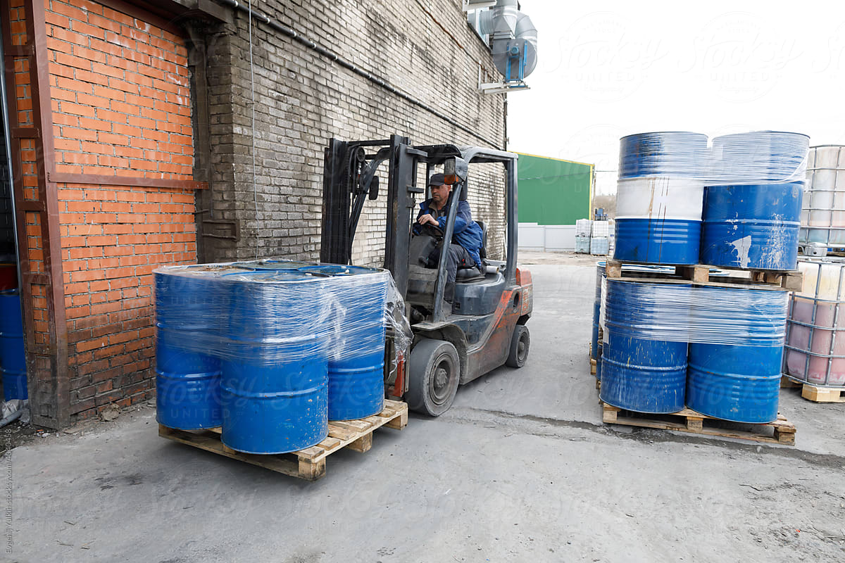 Forklift moving pallet with  blue barrels