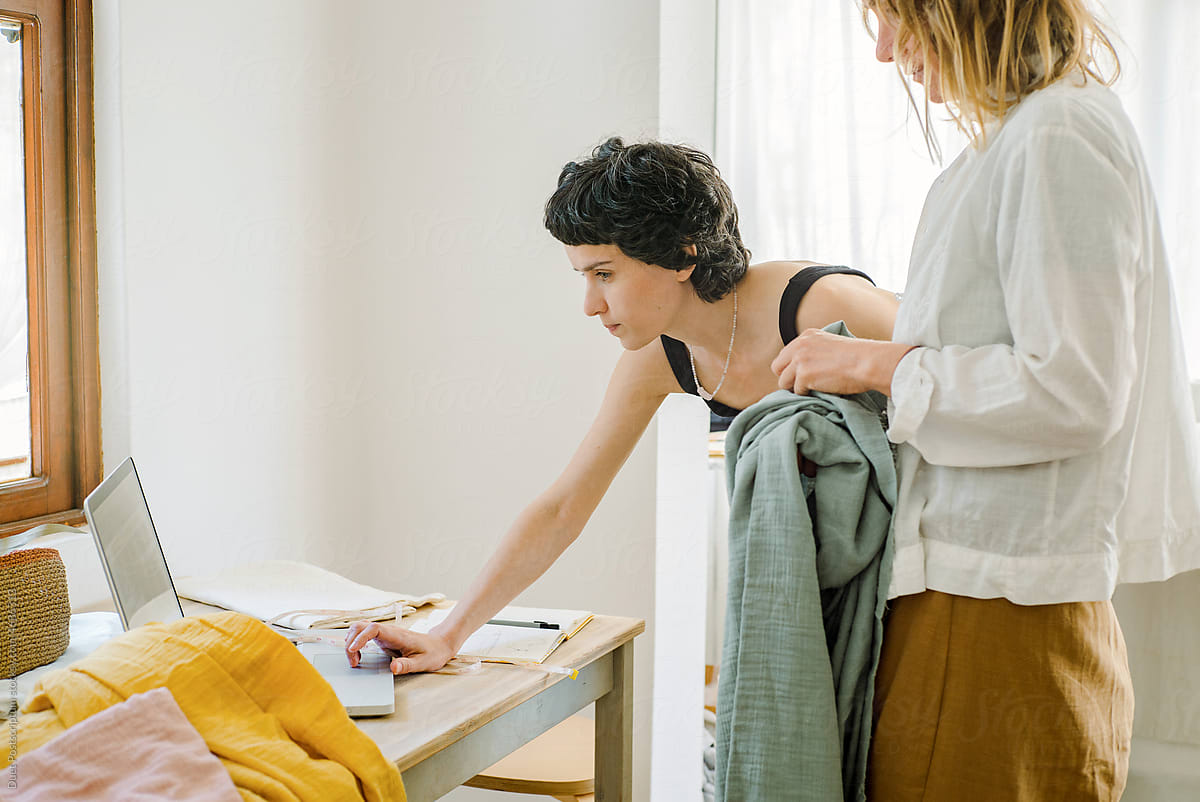 Two women discussing dress design in atelier studio